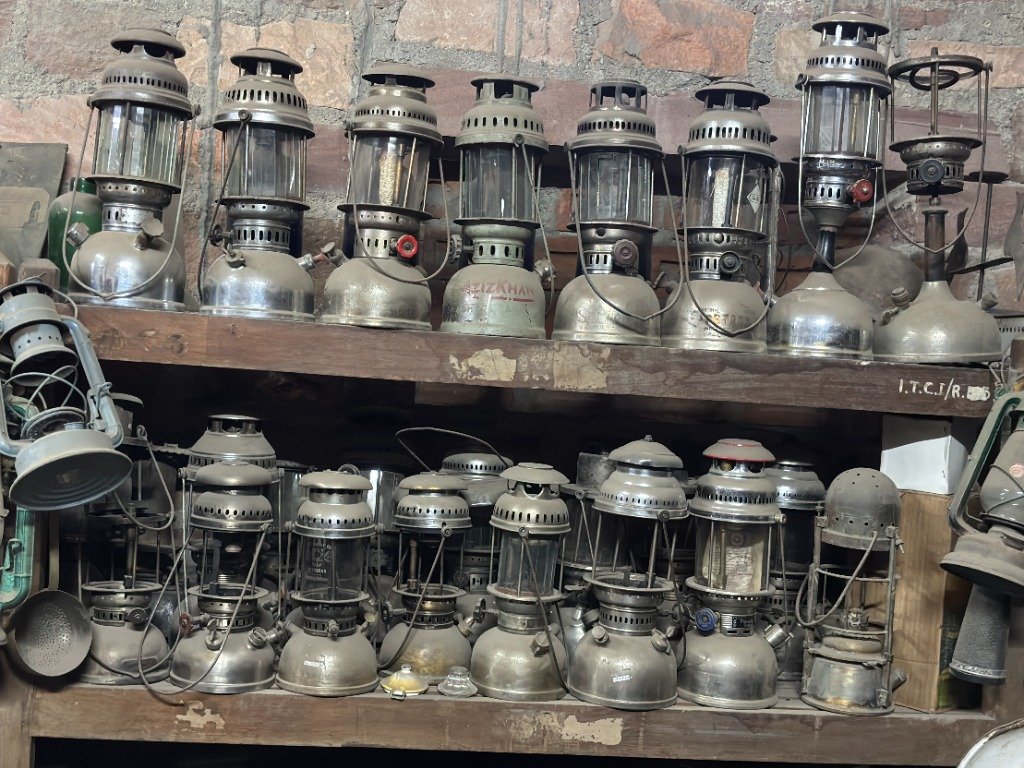 Shelves of vintage Petromax kerosene pressure lanterns and antique hurricane lamps in salvage yard